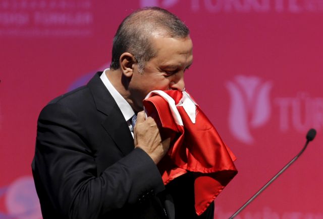FILE PHOTO: Turkey's President Erdogan kisses a handmade Turkish flag, given him as a gift from Ugandan university student Cemil, during a graduation ceremony in Ankara, Turkey