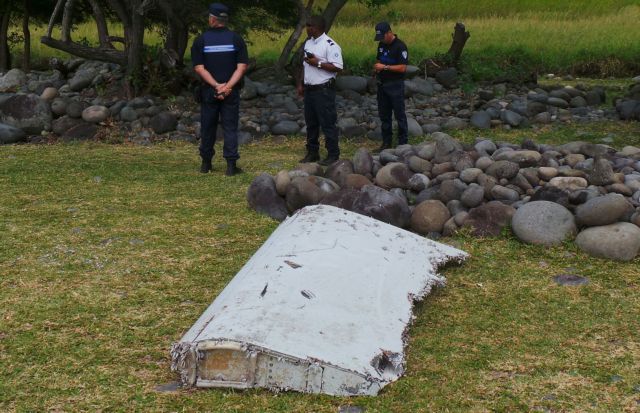 File photo shows French gendarmes and police who stand near a large piece of plane debris which was found on the beach in Saint-Andre, on the French Indian Ocean island of La Reunion
