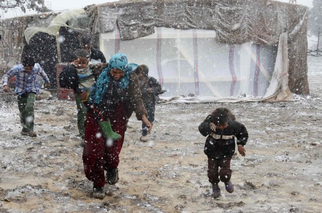 Syrian refugees run for cover from snow during a winter storm in Zahle town, in the Bekaa Valley
